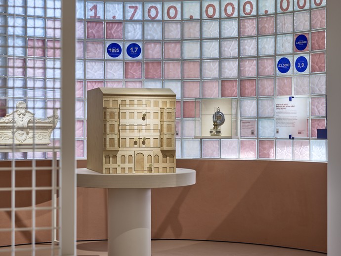 Blick in die Dauerausstellung auf ein Modell Holzhaus mit Screen zum Spielen hinter dem Fenster