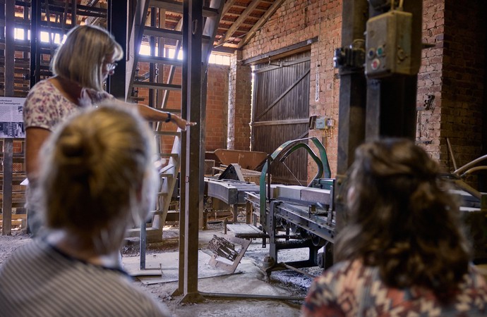 Ein Frau erläutert Besuchern eine Maschine.
