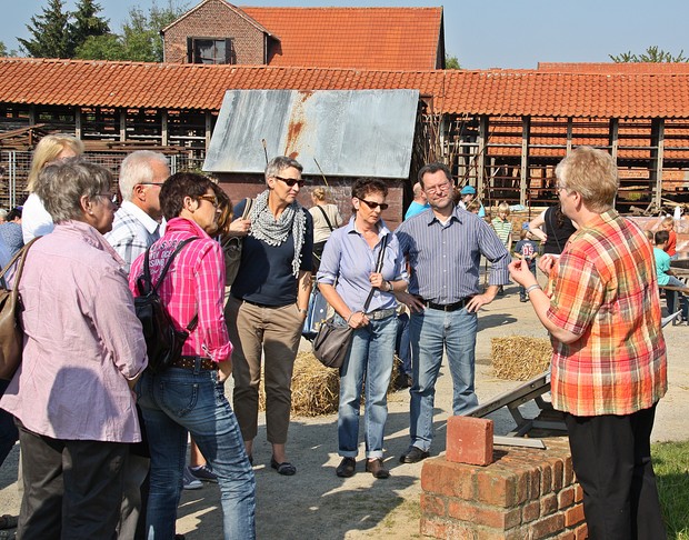 Eine Museumsmitarbeiterin erklärt einer Gruppe Besuchern die Ziegelherstellung.