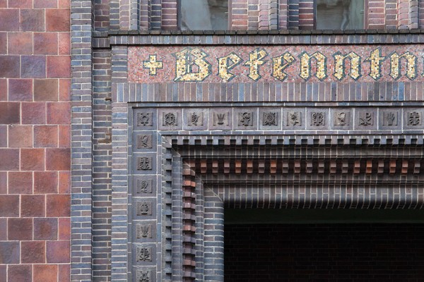Detailaufnahme einer dekorierten Backsteinfassade, umfasst von Zahnkammgesimse