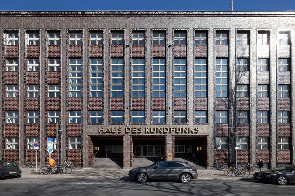 Blick auf die Fassade des Hauses des Rundfunks. Eine gradlinige Fassade durchgehend und regelmäßig von Sprossenfenstern durchbrochen.