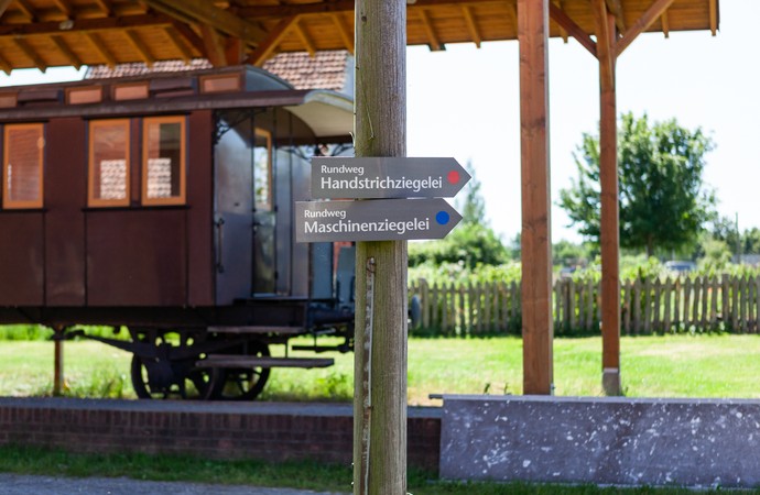 Holzschilder mit der Aufschrift "Rundweg Handstrichziegelei" und "Rundweg Maschineziegelei"