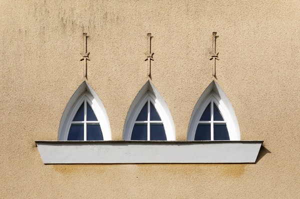 Drei Spitzbogenfenster in einer gelb gehaltenen Fassade