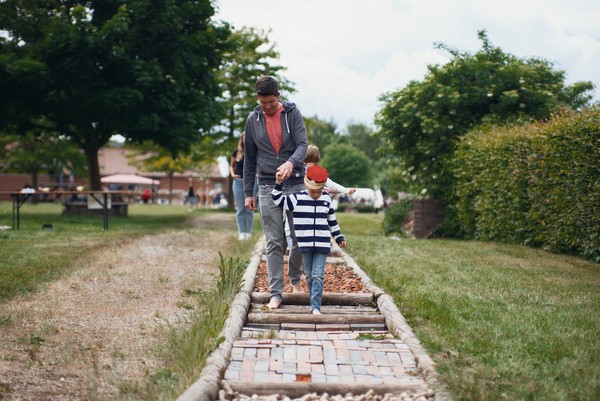 Vater und Sohn gehen über einen Barfußpfad