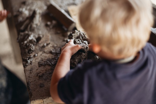 Kind formt mit Händen in nassem Ton