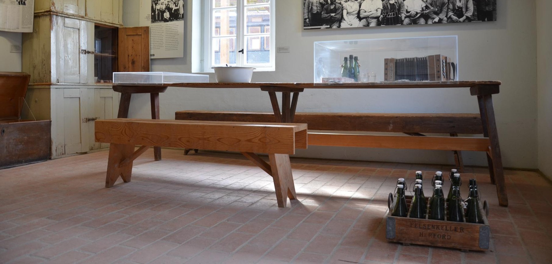 Blick in die Dauerausstellung mit Esstisch, Sitzbank und Schrank.
