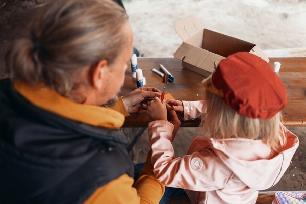 Ein Kind bastelt unter Anleitung einer erwachsenen Person