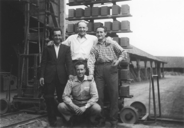 Ziegeleibesitzer Erich Beermann und drei italienische Gastarbeiter posieren vor den Gebäuden der Ziegelei (um 1960).